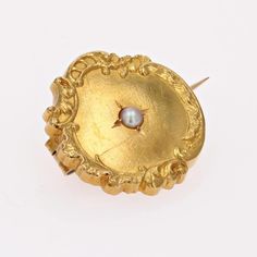 Brooch in 18 karat yellow gold, eagle head hallmark. This round collar brooch in yellow gold is bordered by a floral and arabesque design and features a fine half-pearl in the center. The fastening system is a safety pin. Pearl diameter : 2/2.5 mm approximately. Brooch diameter : 19 mm approximately, thickness : 3 mm approximately. Total weight of the jewel : 2 g approximately. Authentic antique jewel - French work of the 20th Century. Each piece of jewelry is checked and repolished by our Frenc