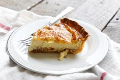 a piece of quiche on a plate with a fork and napkin next to it