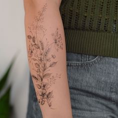 a woman's arm with flowers and leaves tattooed on the left side of her arm