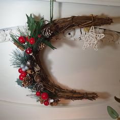 a christmas wreath hanging from the ceiling with pine cones, berries and other holiday decorations