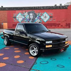 a black pickup truck parked in front of a wall with colorful circles on the ground