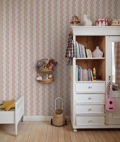 a white dresser sitting next to a wall with a book shelf on top of it