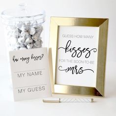 there are some candy in a glass jar next to a sign that says guess how many kisses for the soon - to - be