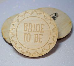 two wooden badges with the words bride to be engraved on them