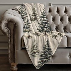 a couch with a christmas tree print on it and a blanket draped over the back