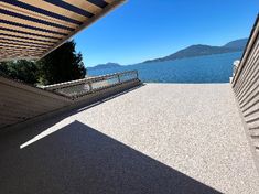 the view from inside an open building looking out at water and mountains in the distance