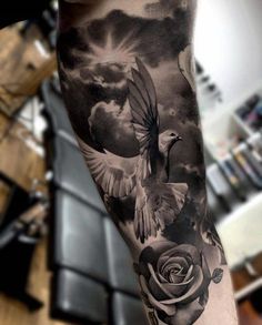 a man's arm with a bird and rose tattoo on it