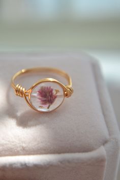 DETAILS Size: 1 x 1 cm Material: UV Resin                  Pink Pressed Flower Petal                  Ice Glitters                   14K Gold Filled Wire     DESCRIPTION Each flower has its symbolism of language of flowers and was usually used to deliver a message.  The unique pink pressed flower ring is wrapped with hypoallergenic 14K gold filled wire. The ring is filled with ice glitters . This cute jewelry is perfect as a gift.  BEFORE PURCHASING Since these are natural flowers, there are no two flowers are the same in the world. Please allow there are slight differences in color or shape between flowers because this is the beauty of nature. I try my best to only use the flowers that look closest to the picture, YOU ARE ALWAYS WELCOME TO MESSAGE ME TO SEE A PICTURE OF YOUR ORDER BEFORE How To Make Resin Jewelry Dried Flowers, Pressed Flower Rings, Resin Gold Jewelry, Resin Art Jewelry Dried Flowers, Uv Resin Flower Jewelry, Preserved Flower Jewelry, Pressed Flower Jewelry Diy, Dried Flowers Jewelry, Cute Flower Jewelry