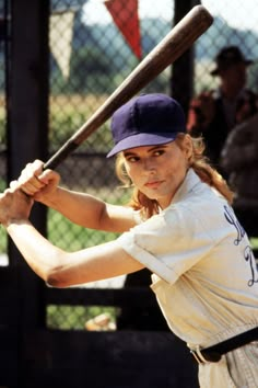 a young woman holding a baseball bat in front of her face and looking at the camera