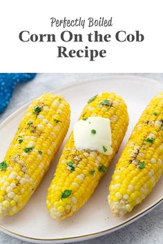 three corn on the cob with butter and parsley on top, sitting on a white plate