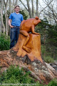 a man standing next to a carved bear on top of a tree stump in the woods