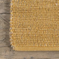 a close up view of a yellow rug on a wooden floor with wood planks in the background