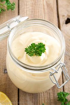 a jar filled with mayonnaise and parsley on top of a wooden table