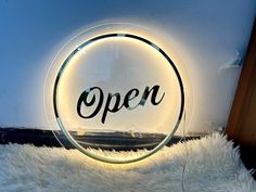 an open sign sitting on top of a white fluffy rug in front of a wall