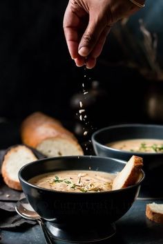 a person sprinkles parmesan cheese onto a bowl of soup