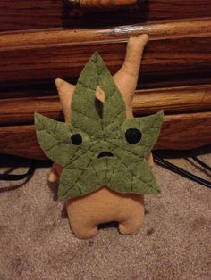 a stuffed animal with a leaf on it's head sitting next to a dresser