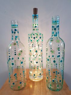 three glass bottles sitting on top of a wooden table next to each other with dots painted on them