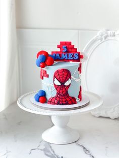 a spiderman themed birthday cake on a white pedestal