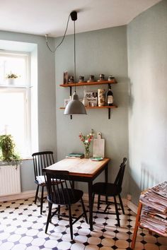 a table and chairs in a small room with shelves on the wall above it,