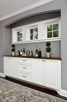 a room with some white cabinets and plants on the counter top in front of it