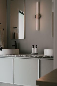 a bathroom with two sinks and a large mirror above the sink is lit by lights