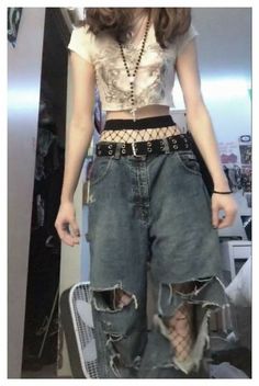 a woman standing in front of a mirror wearing high waisted jeans and a crop top