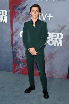 a man in a green suit and black shoes at the red carpeted room awards