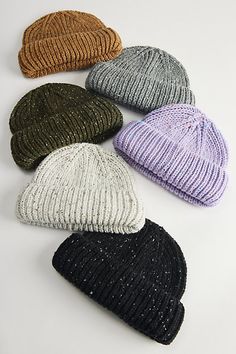 six knitted hats laid out on a white surface