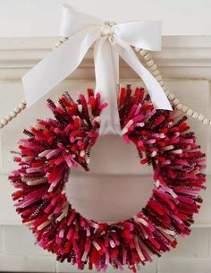 a red wreath with white ribbon hanging on a wall