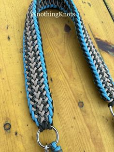 a blue and gray leash with metal ring on wooden floor next to wood planks