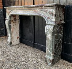 an old fireplace in front of a black wooden door with peeling paint on the mantle