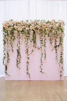 an arrangement of flowers and greenery on a pink wall