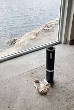 a trash can sitting in front of a window next to the ocean with a piece of cardboard taped to it