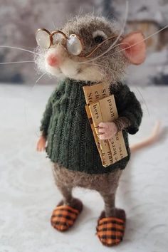 a mouse wearing glasses and holding a piece of paper in it's hand, while standing on snow covered ground