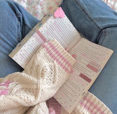 an open book sitting on top of a person's lap next to blue jeans