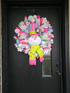 a decorated wreath on the front door of a house with a snowman in it