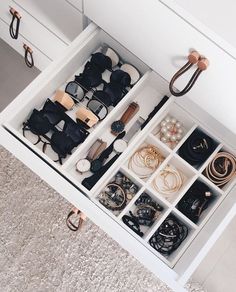 an open drawer with many pairs of shoes and accessories in it on top of carpeted floor