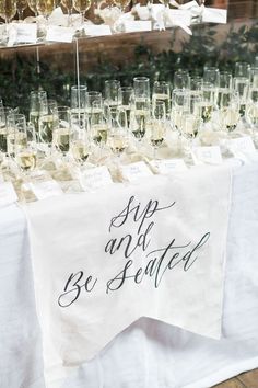 wine glasses are lined up on a table with a sign that says sip and be served