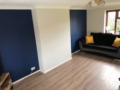 a living room with blue and white walls, wood flooring and a black couch