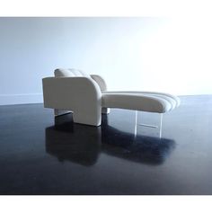 a white couch sitting on top of a black floor next to a chair with metal legs