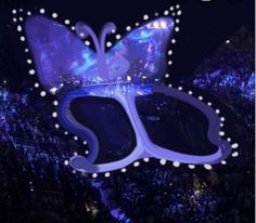 a large butterfly shaped object in the middle of a crowd at a concert with lights on it