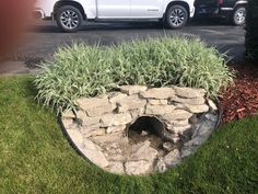 a white truck is parked in front of a rock and grass planter that has been dug into the ground