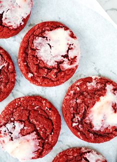 four red velvet cookies with white icing on top