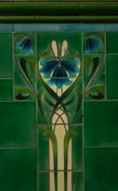 a green tiled wall with blue flowers and leaves painted on it's glass panels