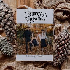 a christmas card sitting on top of a table next to pine cones