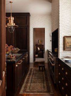 a kitchen with wooden cabinets and black counter tops, along with a rug on the floor