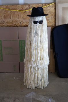 a fake long haired man with sunglasses and a hat on top of a wooden floor