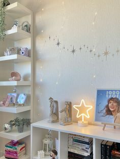 a white shelf topped with books next to a star shaped light on top of it