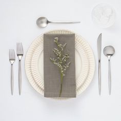 a place setting with silverware, napkins and flowers on the plate in front of it