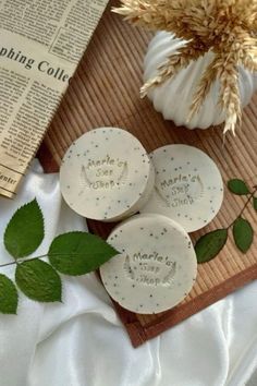 three personalized soaps sitting on top of a wooden cutting board next to flowers